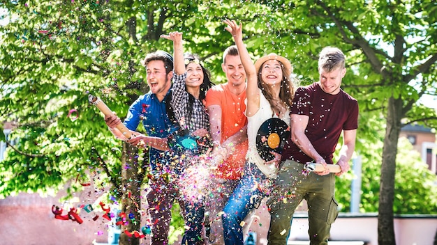 Happy amused friends having fun out side cheering with confetti