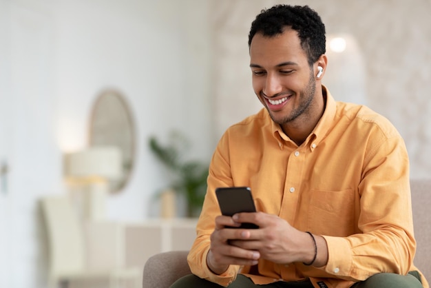 Happy arab man using cellphone wearing wireless headphones