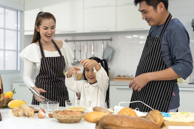 Happy asia family with daughter making dough preparing baking cookies Daughter help parent preparing the bake Family concept