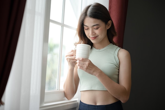 Happy Asia woman holding coffee in mug in living room at home