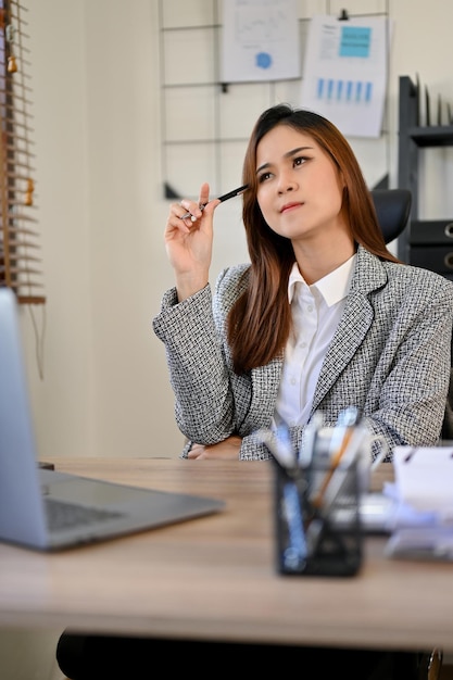 Happy Asian businesswoman thinking of new business ideas or new marketing campaign