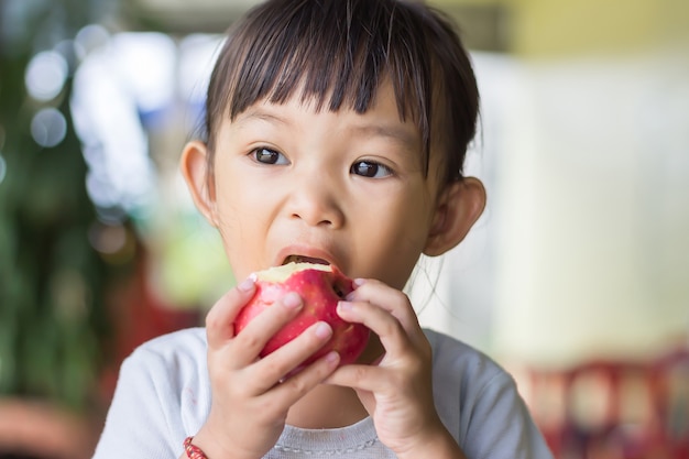 Happy Asian child girl eating and biting an red apple. Enjoy eating moment.