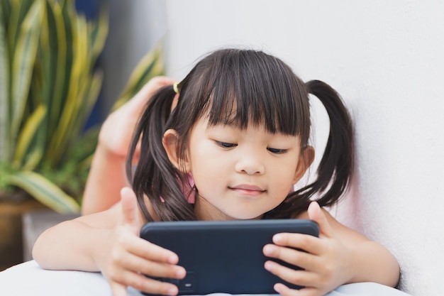 Happy Asian child girl watching and using smart phone