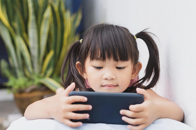 Happy Asian child girl watching and using smart phone