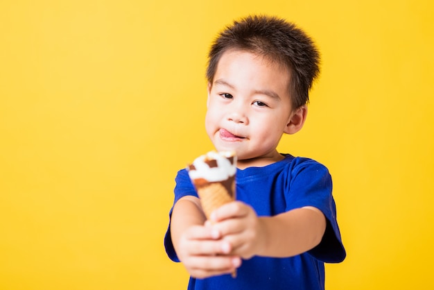 Happy Asian child little boy smile holds and eating sweet chocolate ice cream waffle cone