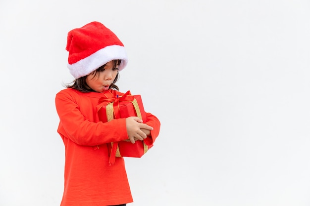 Happy Asian child in Santa red hat holding Christmas presents. Christmas time.on white background.