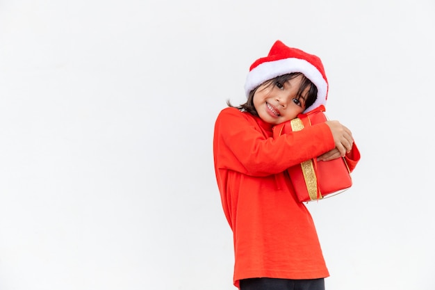 Happy Asian child in Santa red hat holding Christmas presents. Christmas time.on white background.