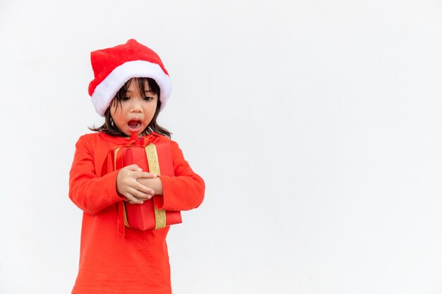 Happy Asian child in Santa red hat holding Christmas presents. Christmas time.on white background.