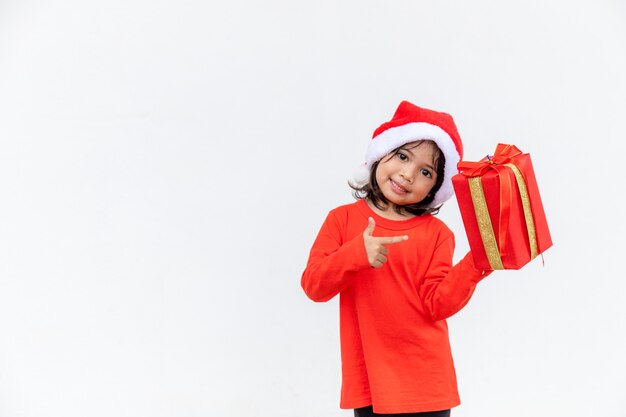 Happy Asian child in Santa red hat holding Christmas presents. Christmas time.on white background.