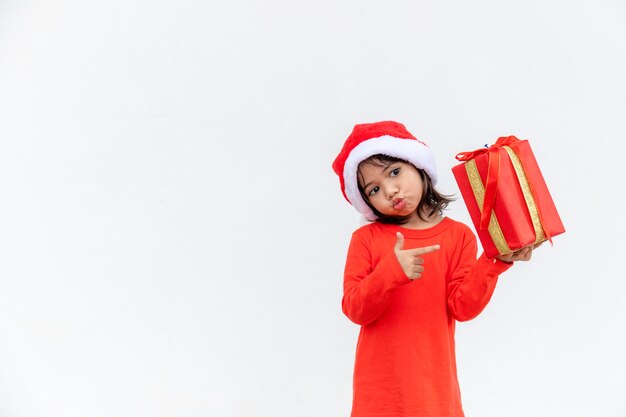 Happy Asian child in Santa red hat holding Christmas presents. Christmas time.on white background.