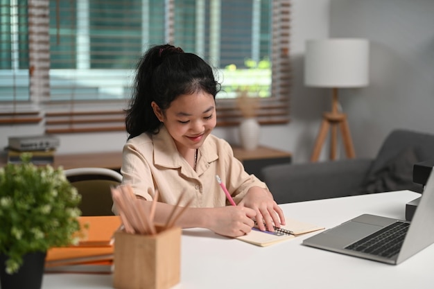 Happy Asian children doing homework studying online with laptop at home