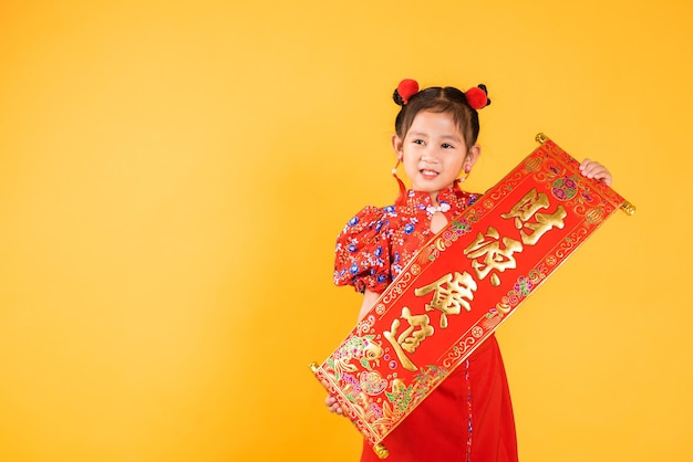 Happy Asian Chinese little child girl smile wearing red cheongsam qipao Spring festival couplets