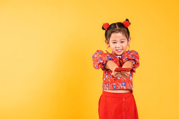 Happy Asian Chinese little girl smile wear red cheongsam handed angpao or red packet monetary gift