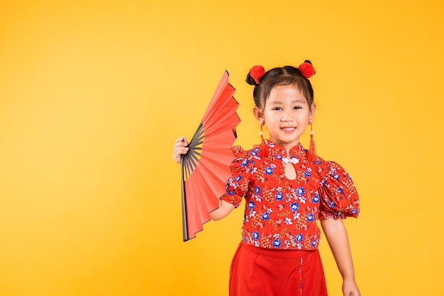 Happy Asian Chinese little girl smile wearing red cheongsam holding fan