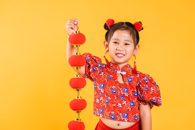 Happy Asian Chinese little girl smile wearing red cheongsam qipao holding silk lanterns