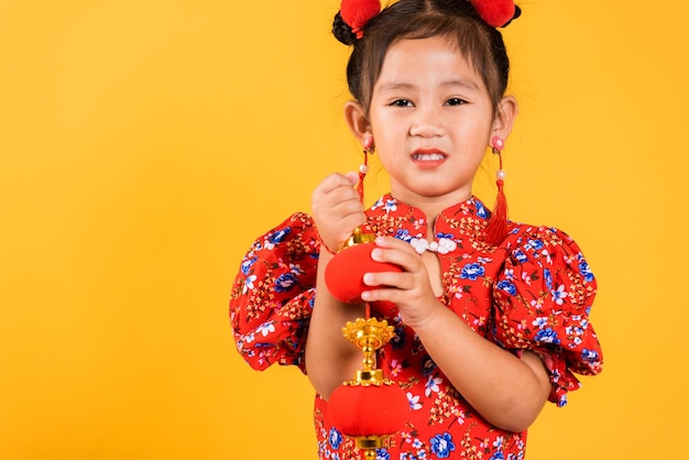 Happy Asian Chinese little girl smile wearing red cheongsam qipao holding silk lanterns