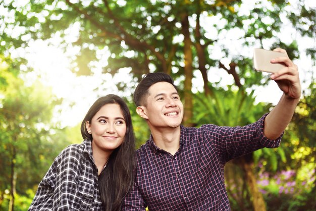 Happy asian couple taking a selfie with phone