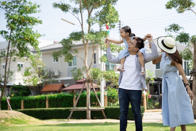 Happy Asian family. Father gave his daughter a piggyback at a park at natural sunlight and house. Family vacation concept