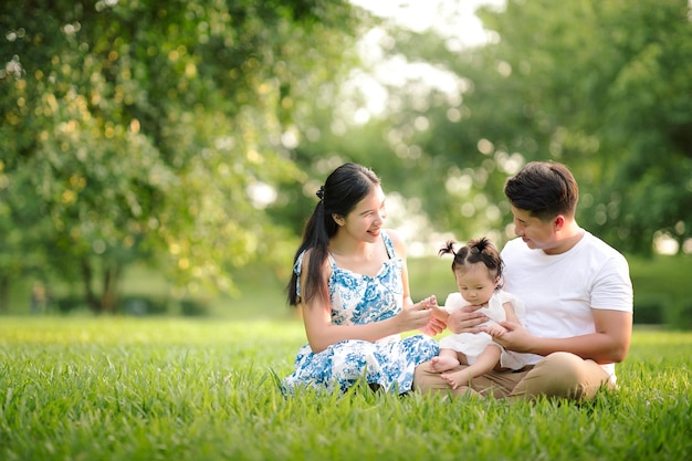 Happy Asian family father mother and little child daughter playing in the park enjoying the beautiful nature at sunset Happy family holidays concept