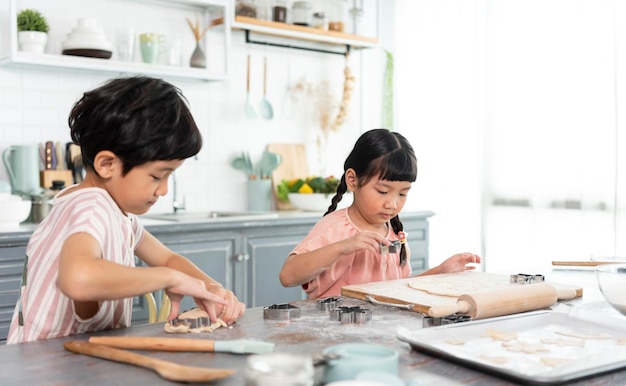 Happy asian family funny kids are preparing the dough bake cookies in the kitchen