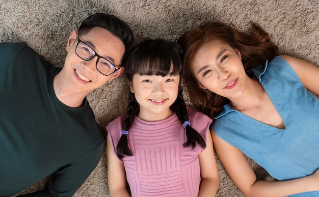 Happy Asian family lying on living room with happy and smile top view