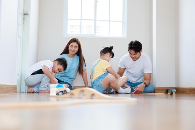 Happy asian family playing wood block create rail road together at home