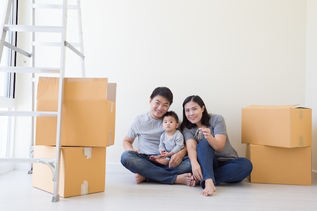 Happy Asian family with cardboard boxes in new house at moving day, Real estate and home concept