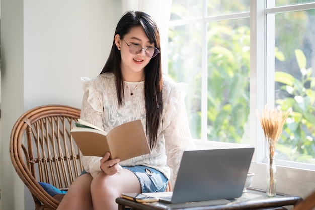 Happy of asian freelance people Businesswoman Taking written Notes to on notebook casual working with laptop computer with a coffee cup mug and smartphone at the cafe,Business Lifestyle