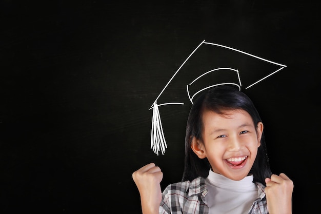 happy Asian girl over blackboard with graduation hat drawn on her head