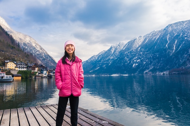 Happy asian girl in pink winter cloth standing by the lake in Hallstatt, Austria