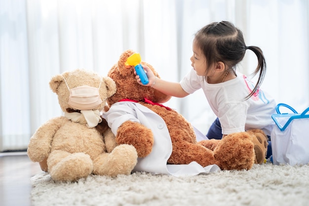 A happy asian girl playing doctor or nurse listening a stethoscope to toy