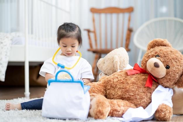 A happy asian girl playing doctor or nurse listening a stethoscope to toy