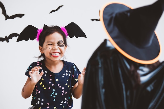 Happy asian little child girl in costumes and makeup having fun on Halloween celebration