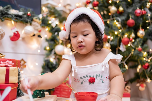 Happy Asian little girl cooking gingerbread at home with parent for Christmas day. Homemade Xmas cookies for kid.