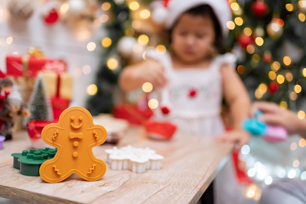 Photo happy asian little girl cooking gingerbread at home with parent for christmas day. homemade xmas cookies for kid.