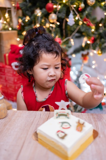 Happy Asian little girl with Christmas cake at home on winter holiday with family.