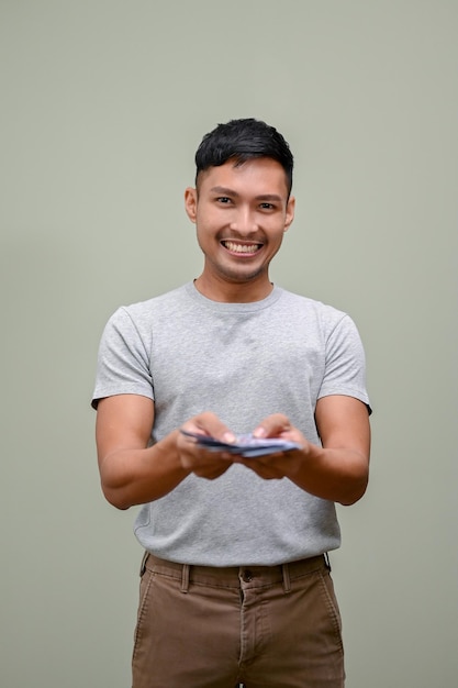 Happy Asian man handing money to camera holding USD dollar bills financial concept