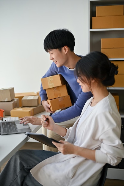 A happy Asian man is an online seller checking orders on the website