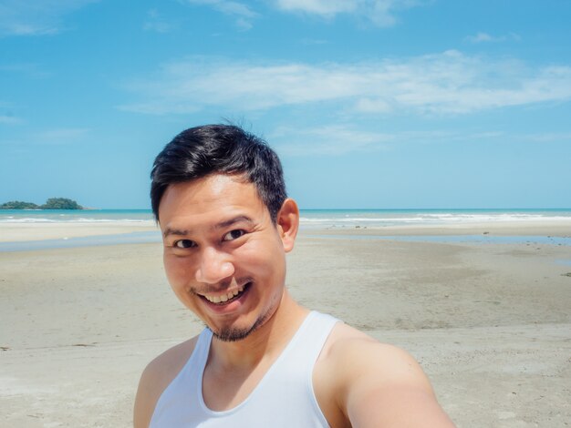 Happy Asian man selfie himself on the sunny summer beach