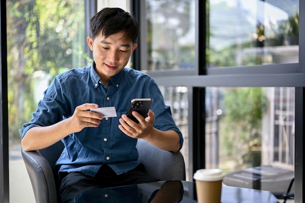 Happy Asian man using mobile banking application to pay his bills online