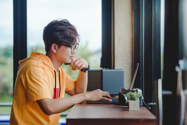 Happy Asian man working at a coffee shop on laptop