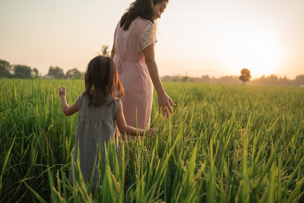 Happy asian mother and kid walking in rice field