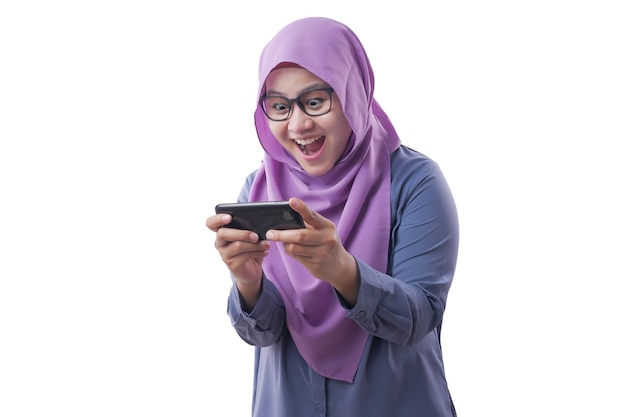 Happy Asian muslim woman excited to play games on her smart phone isolated on white