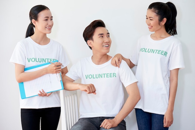 Happy Asian team of young volunteers smiling and looking each other