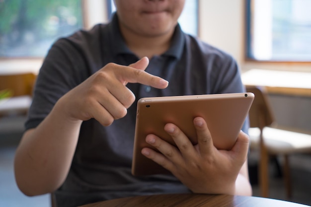 Happy Asian teenager using smart phone and tablet at coffee shop Asian man holding tablet call mom