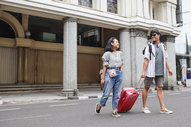 Happy Asian tourist couple walking on street together Travel holiday and relationship concept