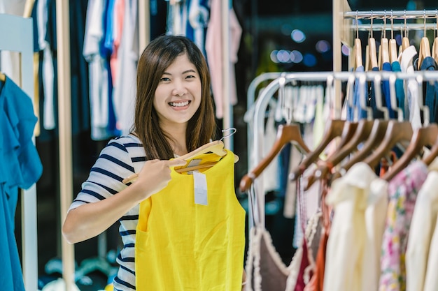 Happy Asian woman choosing clothes in store shop with happy action at department center