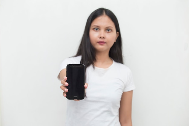 Happy Asian woman demonstrating mobile cell phone Portrait of smiling girl posing on white background