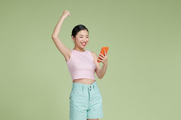 Happy Asian woman holding a smartphone and winning the prize