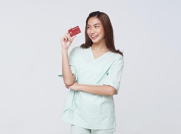 Happy asian woman patient showing credit card isolated on white background